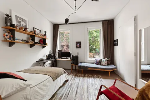 a bedroom with a bed and large windows