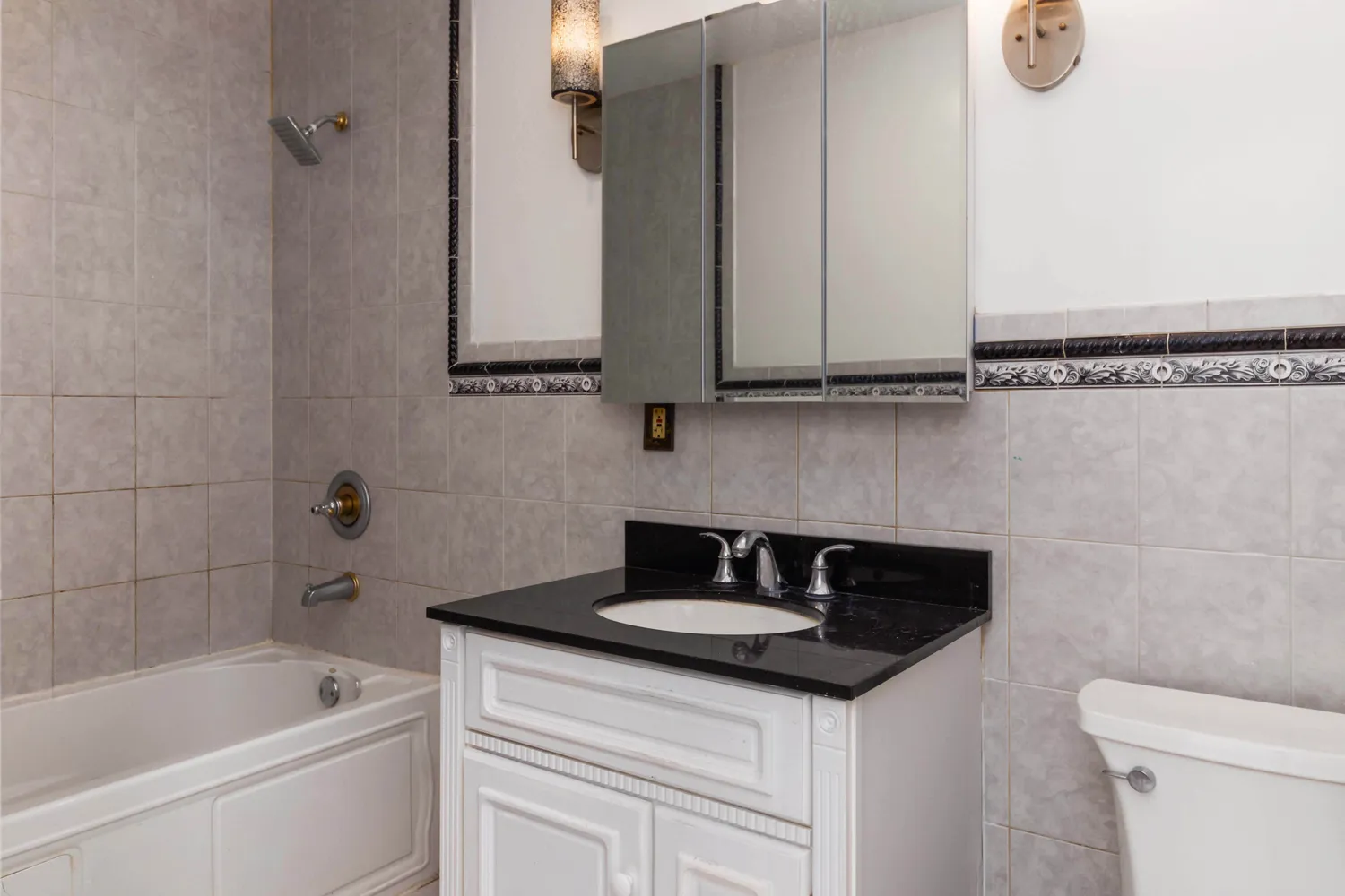 a bathroom with a granite countertop sink a toilet and bathtub