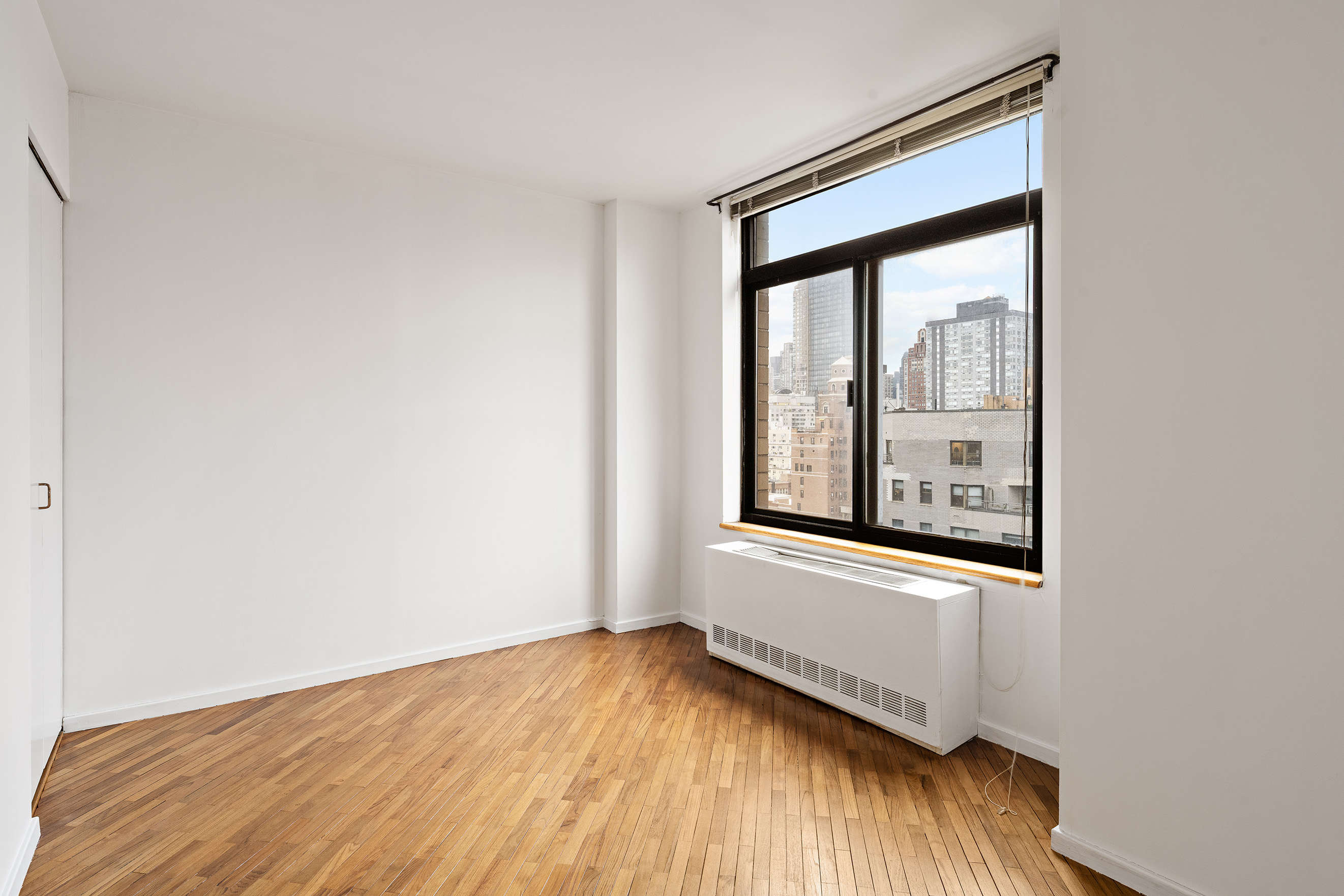 400 East 70th Street, Unit 1903 Manhattan, NY 10021 - Photo 4 of 6 a view of an empty room with wooden floor and a window
