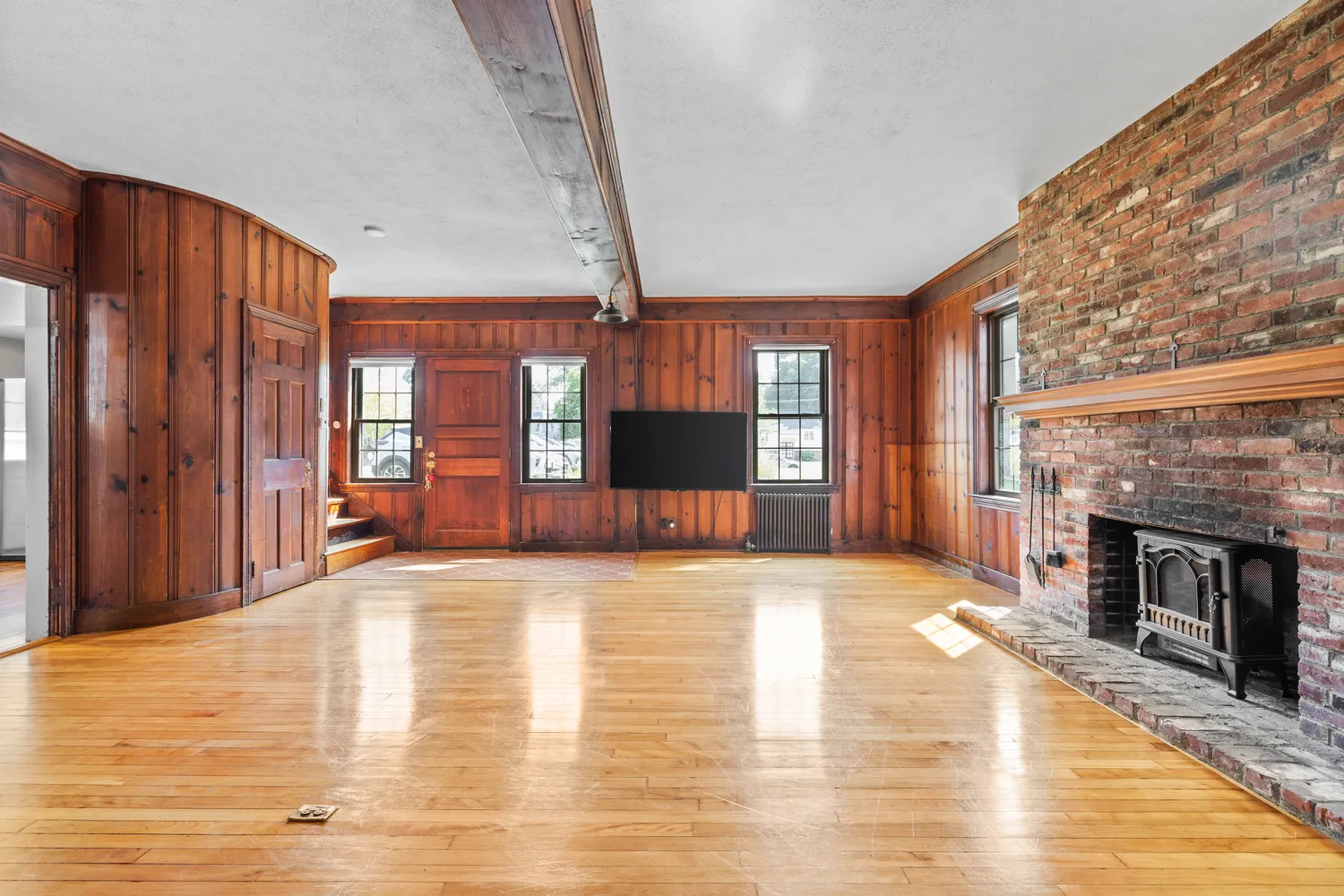 a view of empty room with fireplace and wooden floor