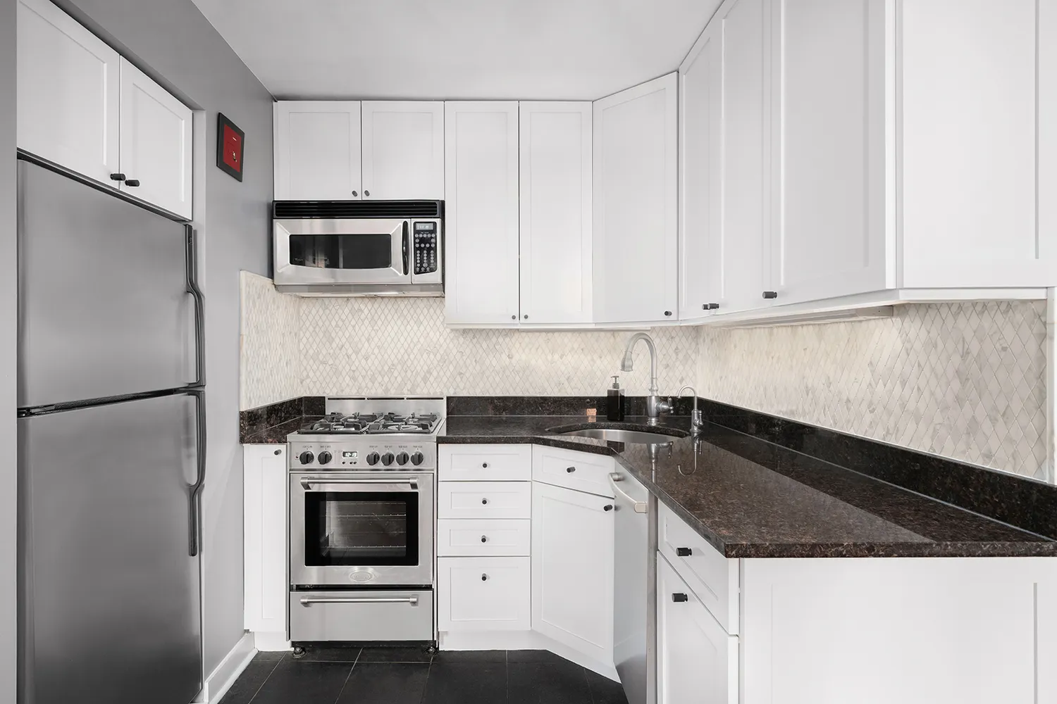 a kitchen with granite countertop white cabinets and stainless steel appliances