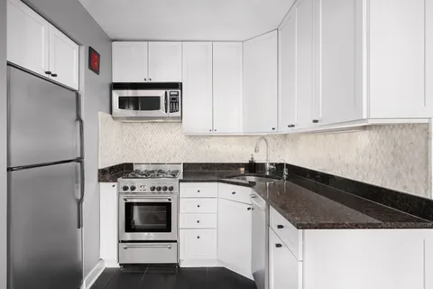 a kitchen with granite countertop white cabinets and stainless steel appliances