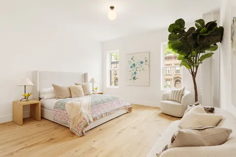 a bedroom with a bed potted plant with the wooden floor