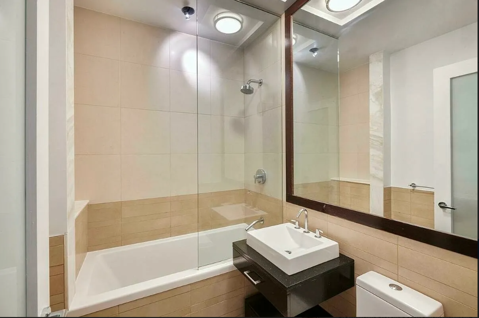 11 East 36th Street, Unit 1203 Manhattan, NY 10016 - Photo 4 of 8 a bathroom with a tub sink and mirror