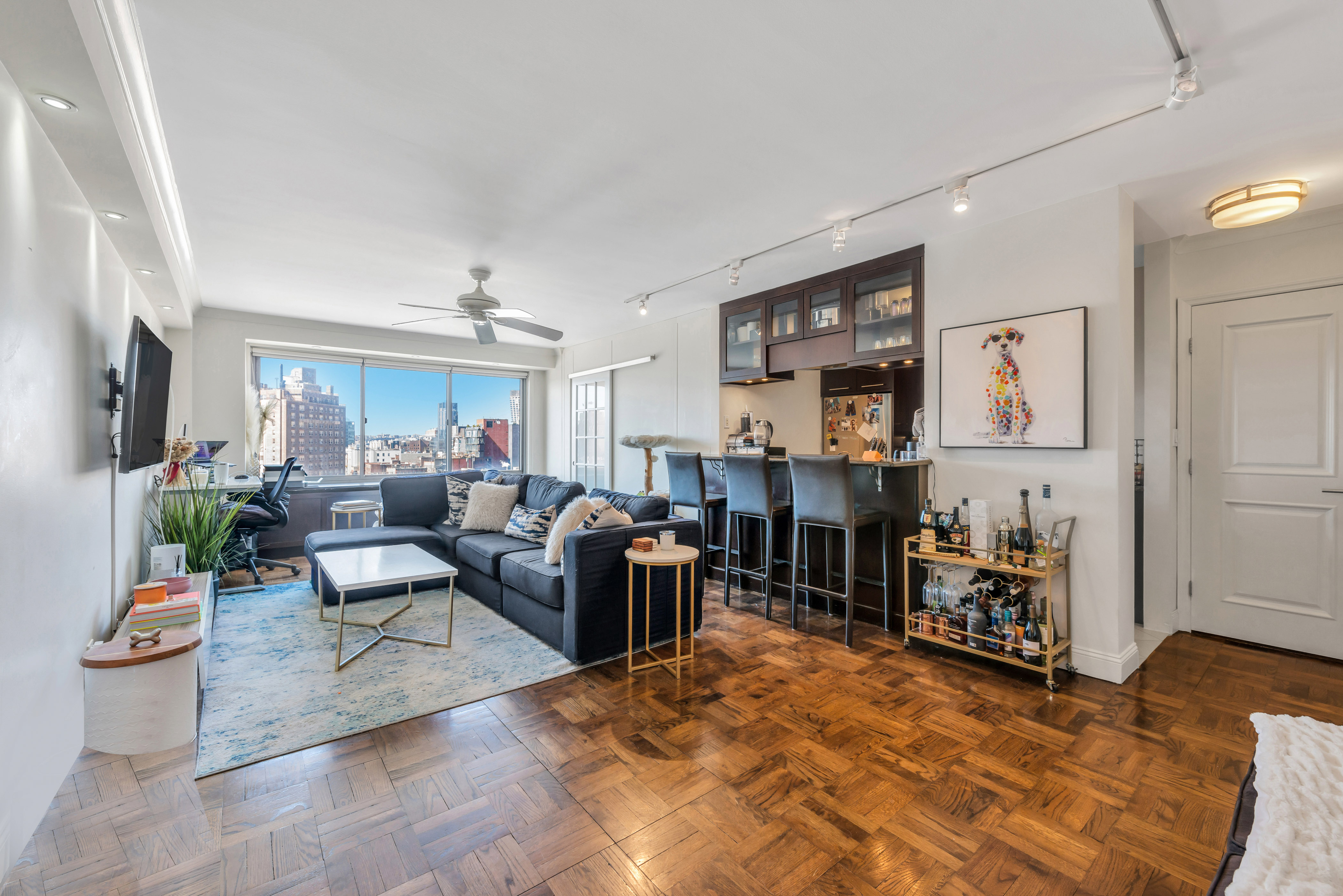 a living room with furniture and a dining table with kitchen appliances