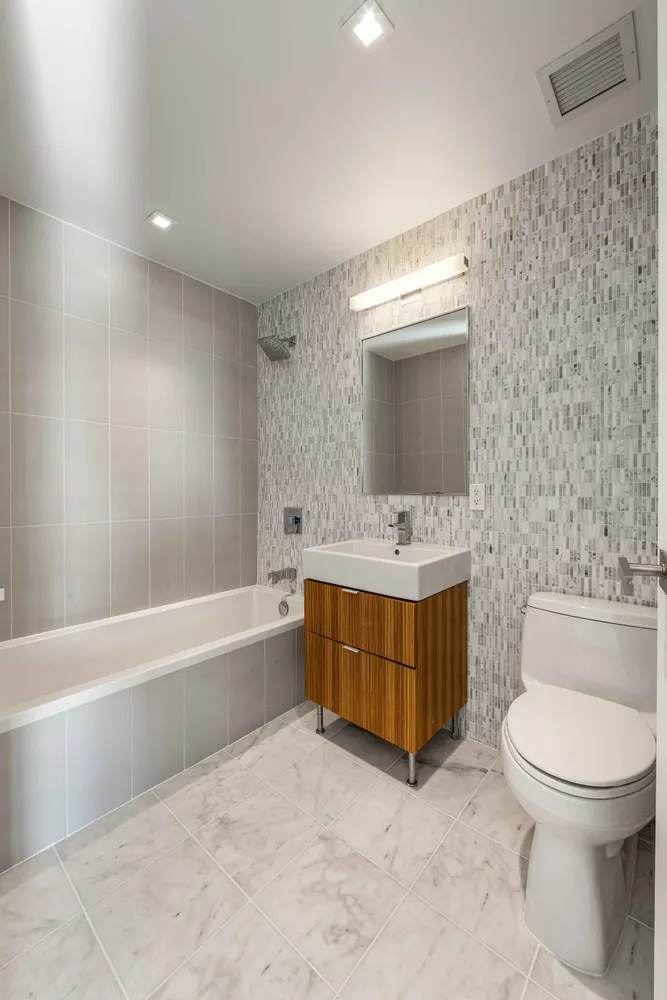 a bathroom with a tub sink toilet and mirror