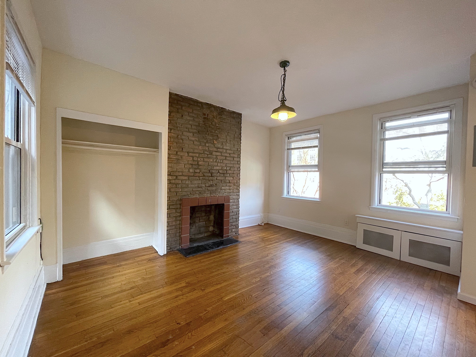 an empty room with wooden floor fireplace and windows