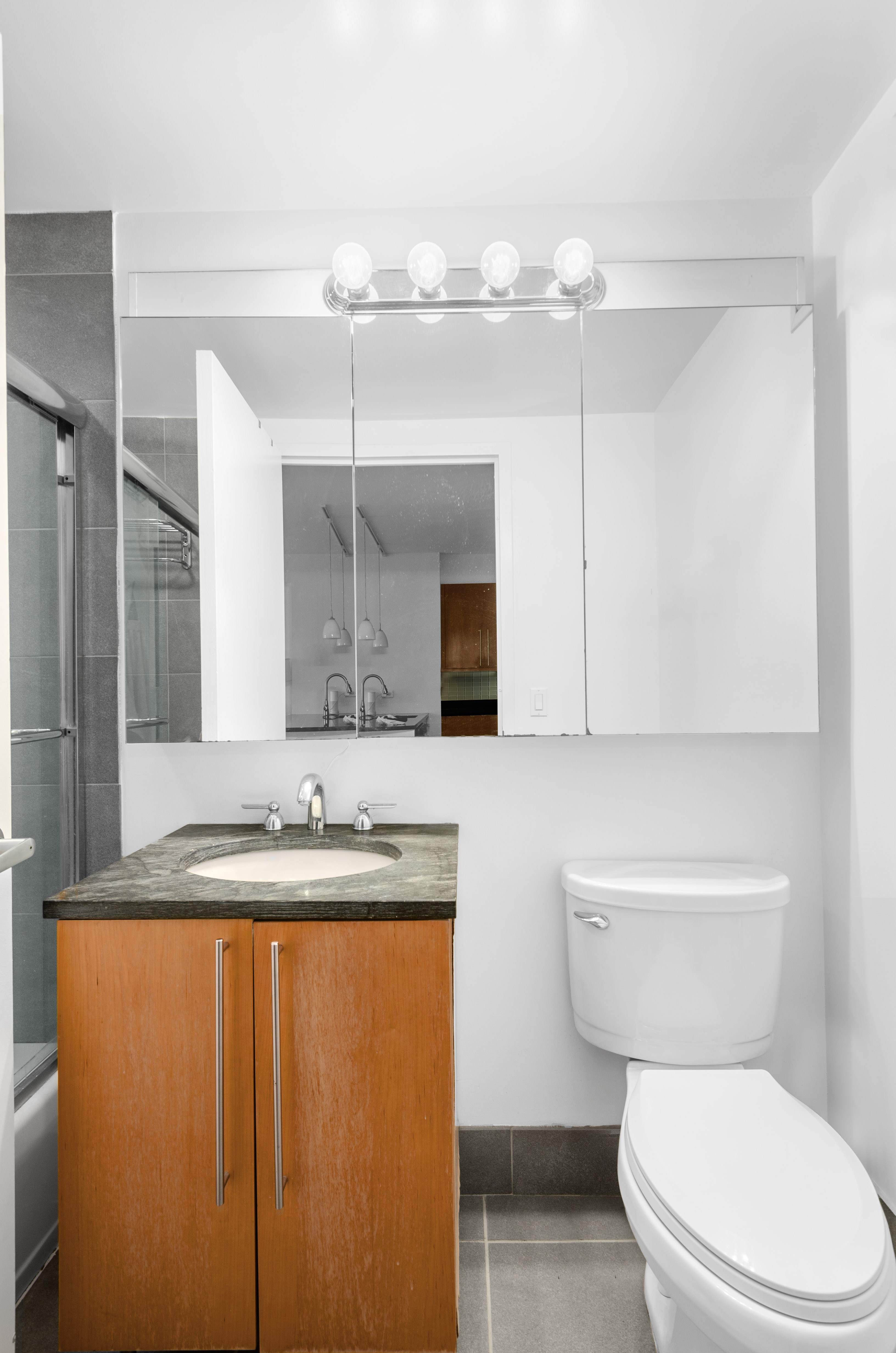 242 East 25th Street, Unit 5B Manhattan, NY 10010 - Photo 7 of 12 a bathroom with a granite countertop sink a toilet and a mirror