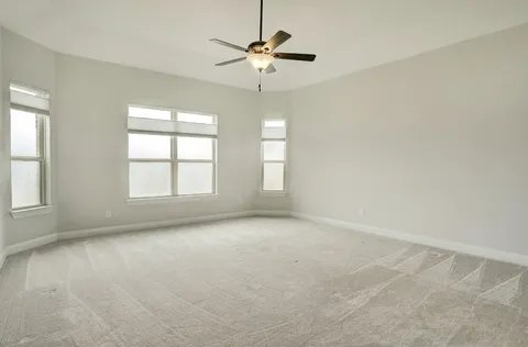 an empty room with a ceiling fan and window