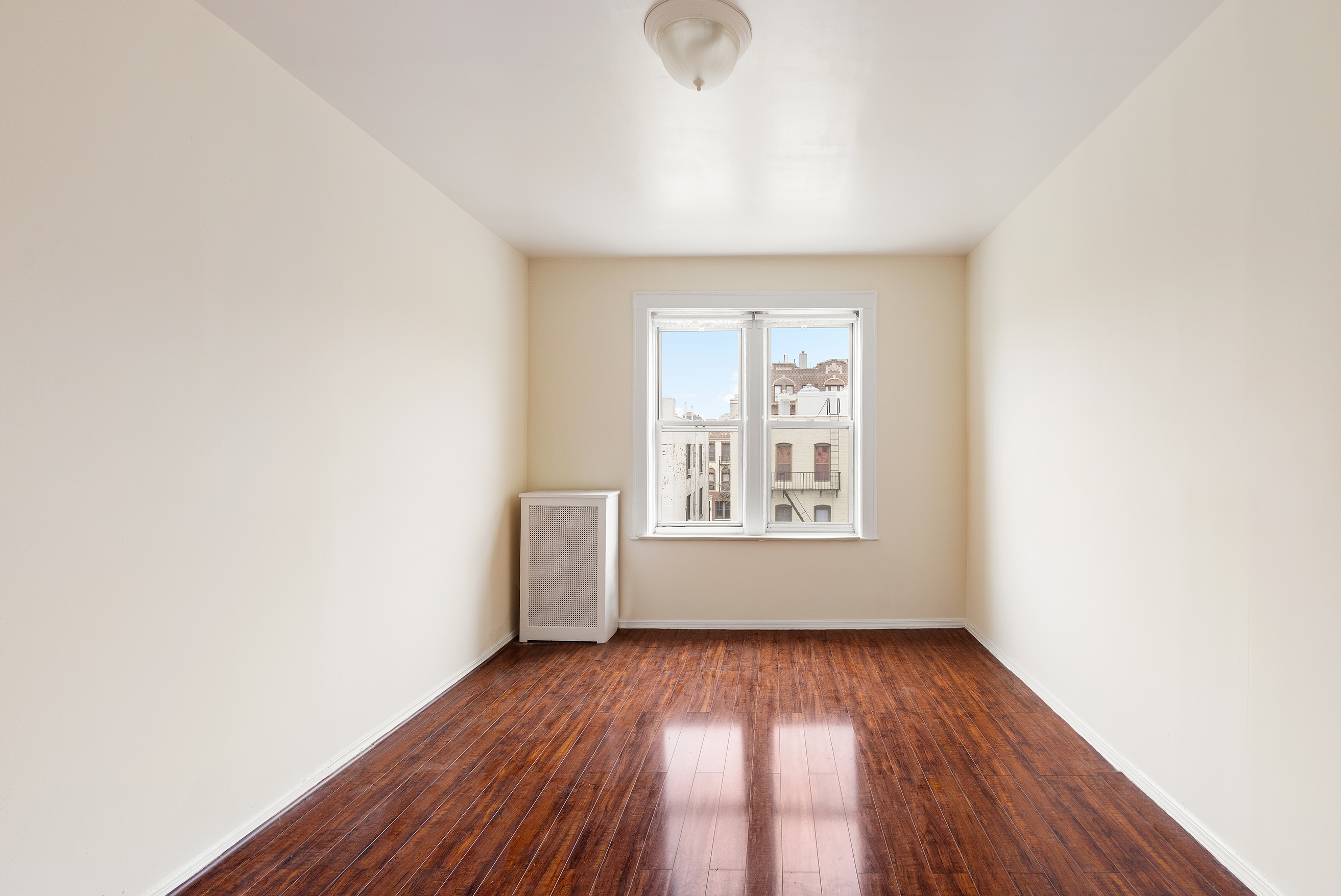 31-22 36th Street Queens, NY 11106 - Photo 3 of 10 an empty room with wooden floor and windows