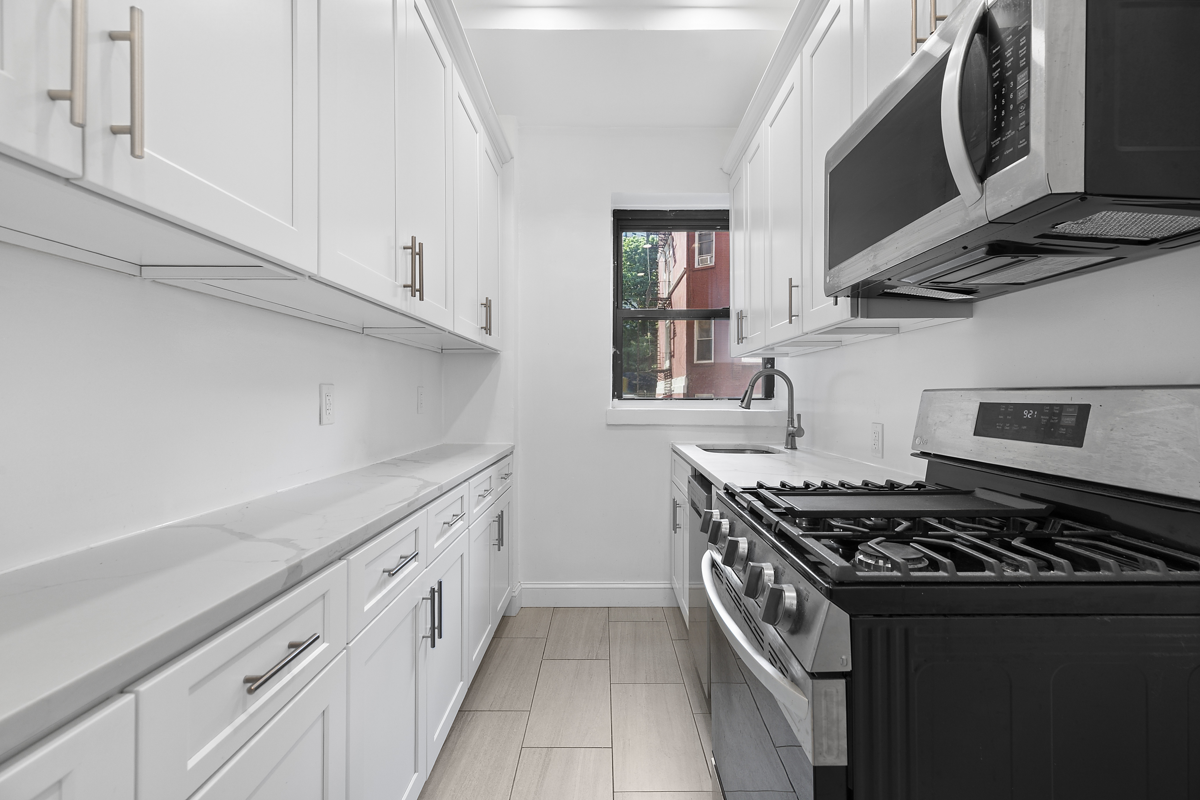 159-34 Riverside Drive West, Unit 1J90 Manhattan, NY 10032 - Photo 6 of 19 a kitchen with stainless steel appliances a sink stove and cabinets