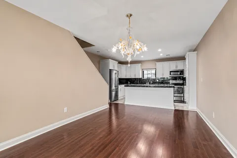 a kitchen with stainless steel appliances granite countertop a refrigerator a stove top oven a sink dishwasher and white cabinets with wooden floor