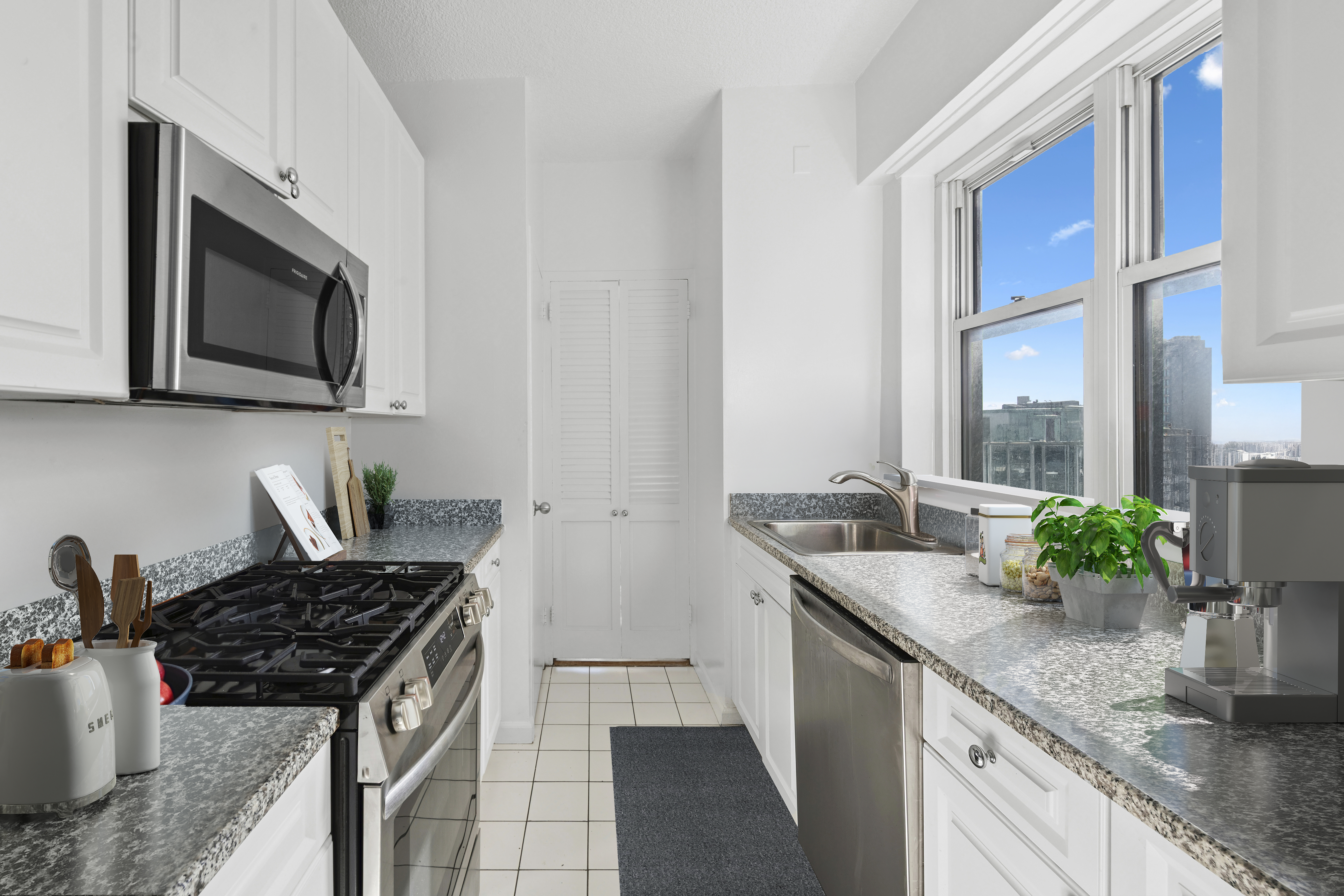 60 East 8th Street, Unit 20N Manhattan, NY 10003 - Photo 3 of 8 a kitchen with stainless steel appliances granite countertop a sink stove and microwave