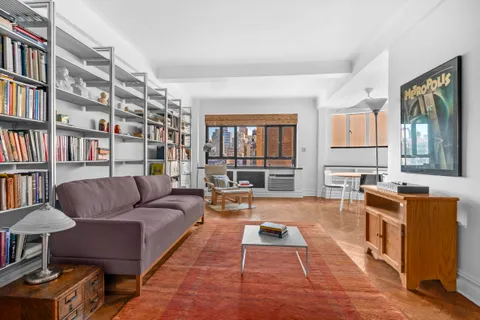 a living room with furniture a bookshelf and a window
