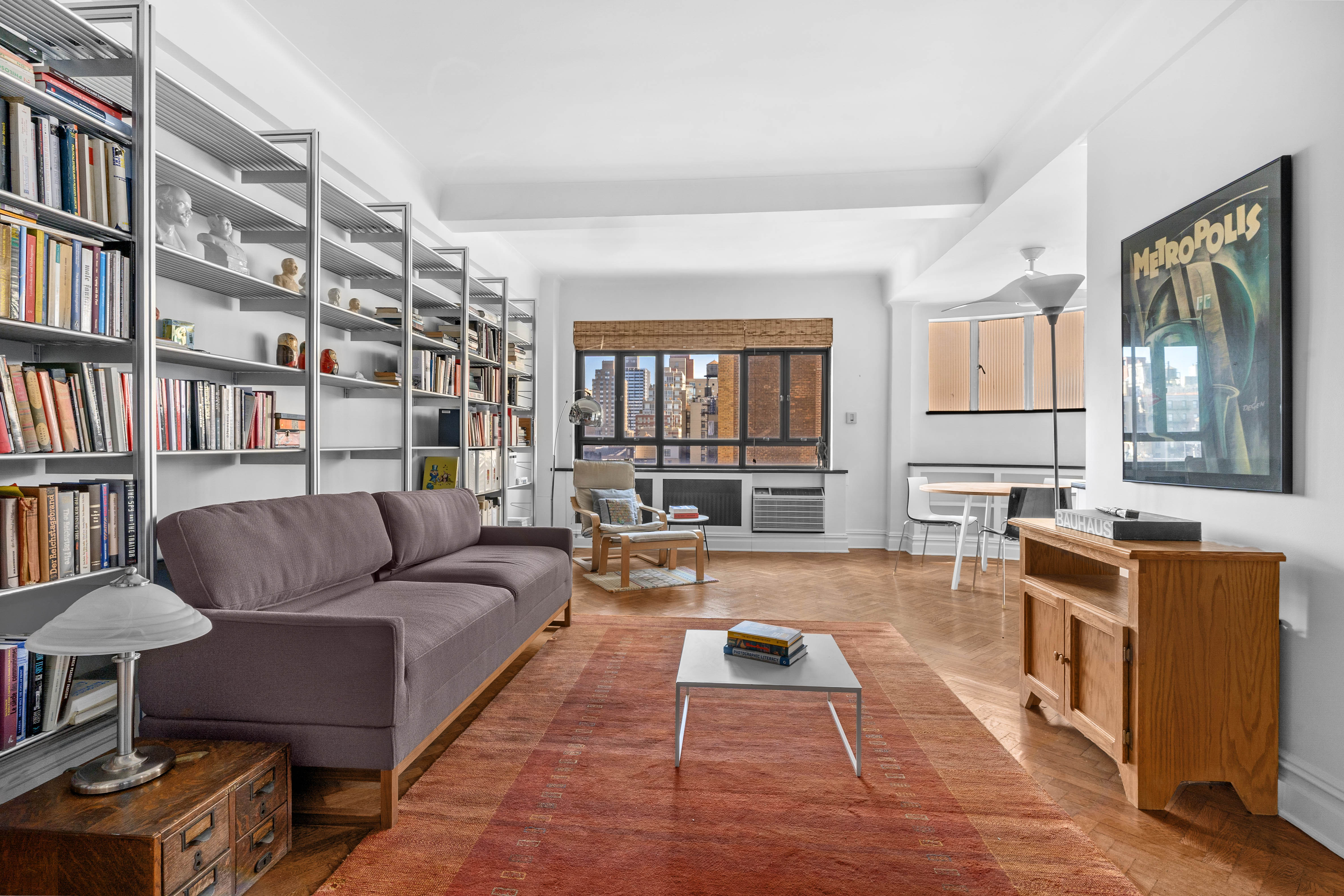 140 Riverside Drive, Unit 12E Manhattan, NY 10024 - Photo 1 of 6 a living room with furniture a bookshelf and a window