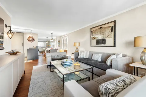 a living room with furniture kitchen view and a window