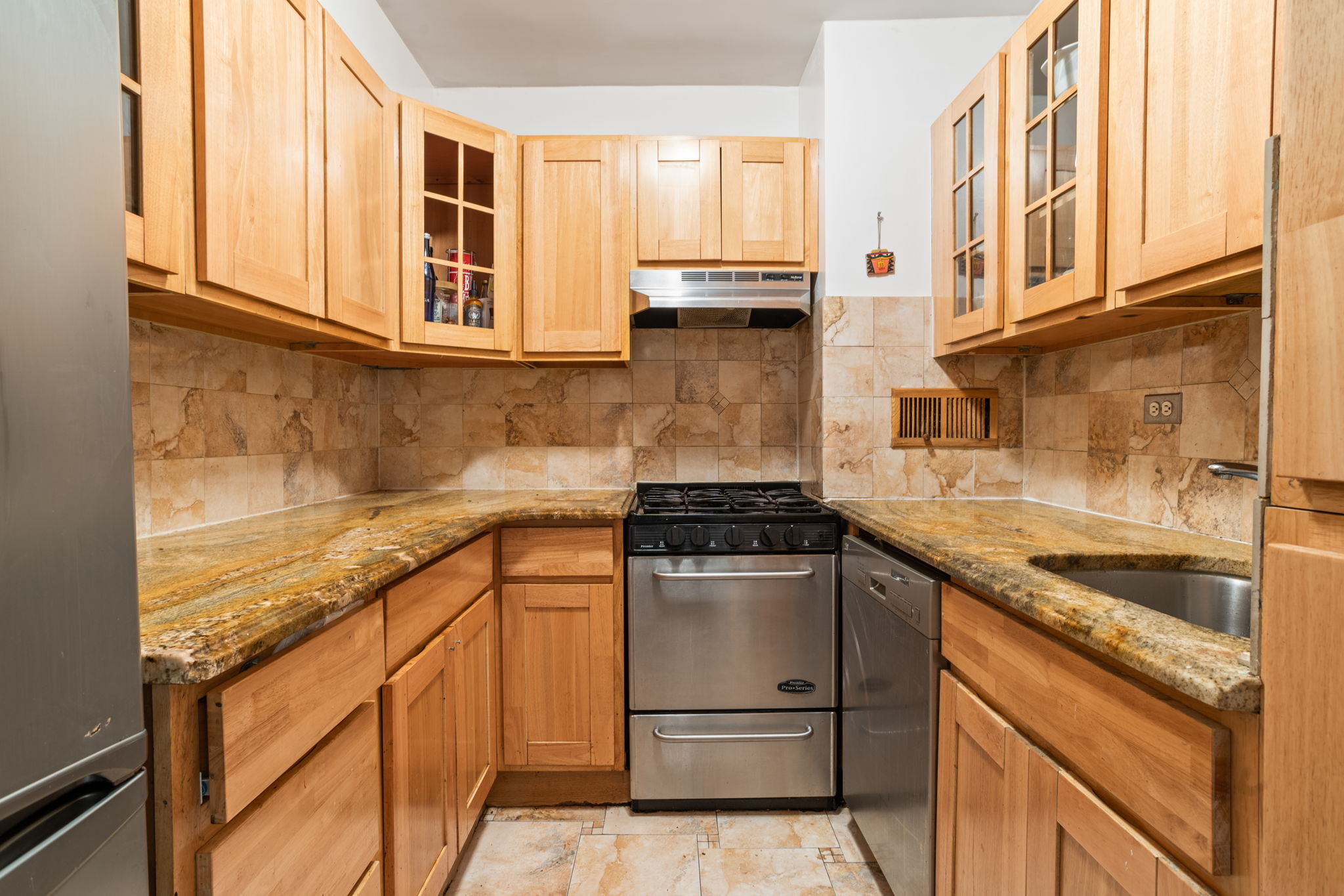 401 East 65th Street, Unit 12F Manhattan, NY 10065 - Photo 5 of 18 a kitchen with stainless steel appliances granite countertop a sink stove and cabinets
