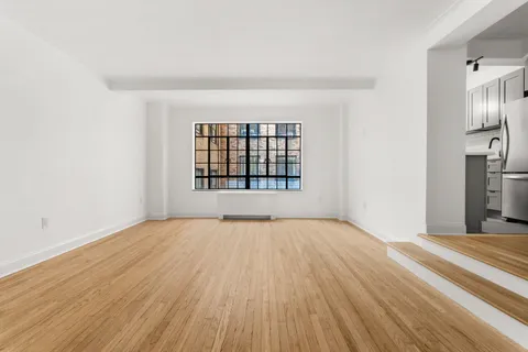 a view of an empty room with a window and wooden floor