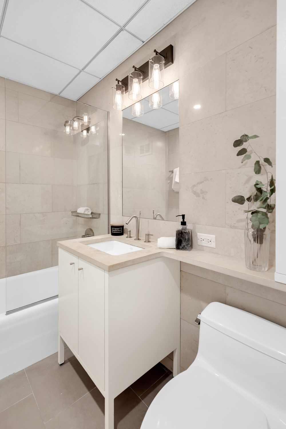 205 East 59th Street, Unit 19A Manhattan, NY 10022 - Photo 9 of 14 a bathroom with a sink a toilet and a large mirror