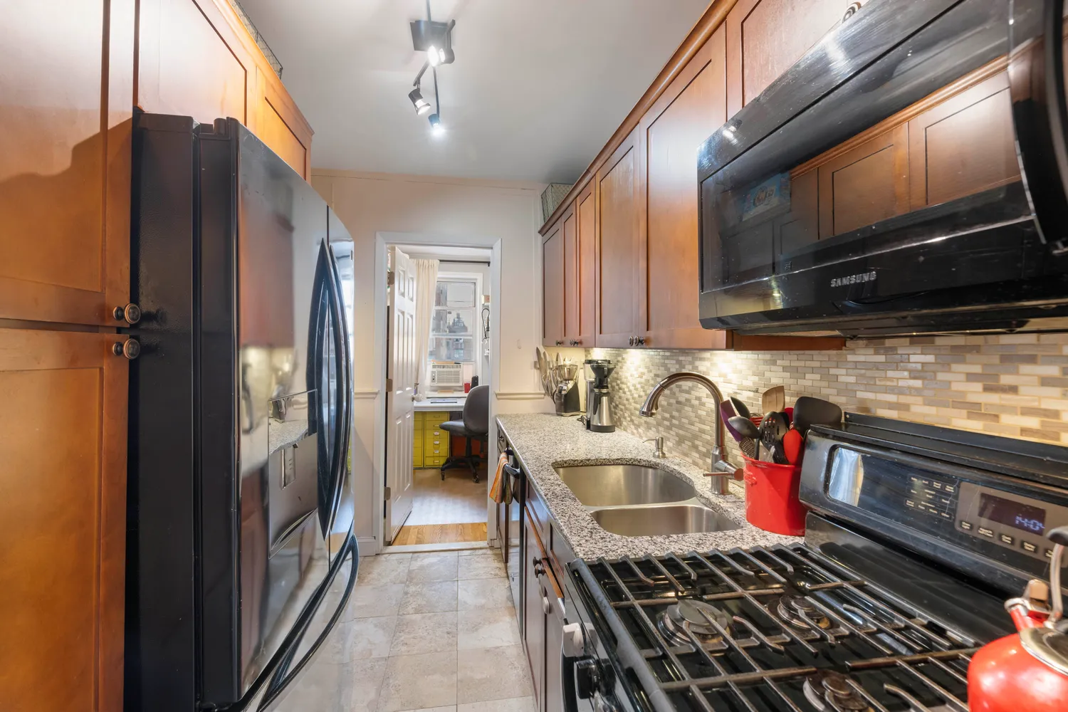 a kitchen with stainless steel appliances granite countertop a refrigerator a stove and a sink