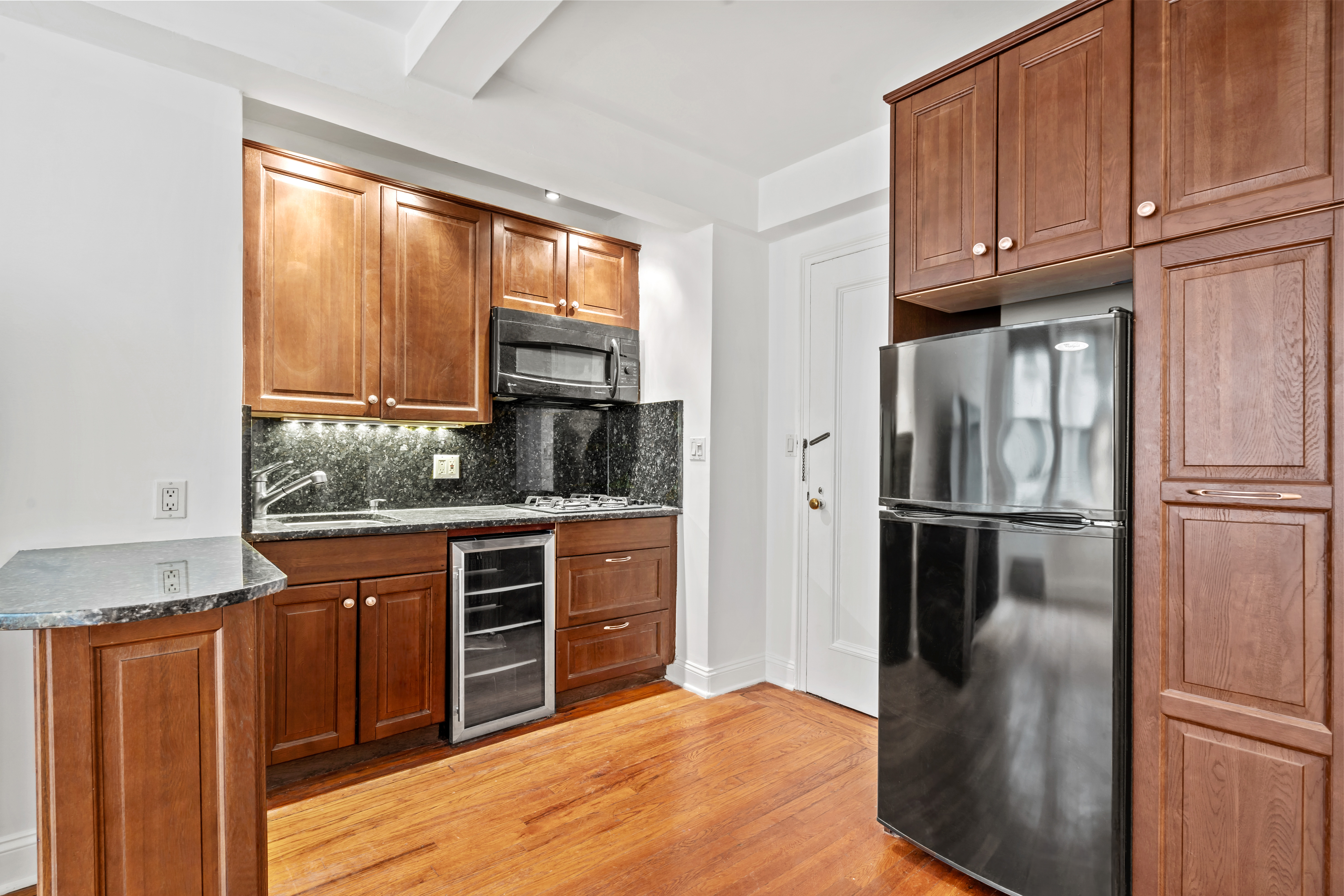 155 East 49th Street, Unit 8C Manhattan, NY 10017 - Photo 4 of 10 a kitchen with stainless steel appliances granite countertop a refrigerator a stove a sink and dishwasher with wooden cabinet
