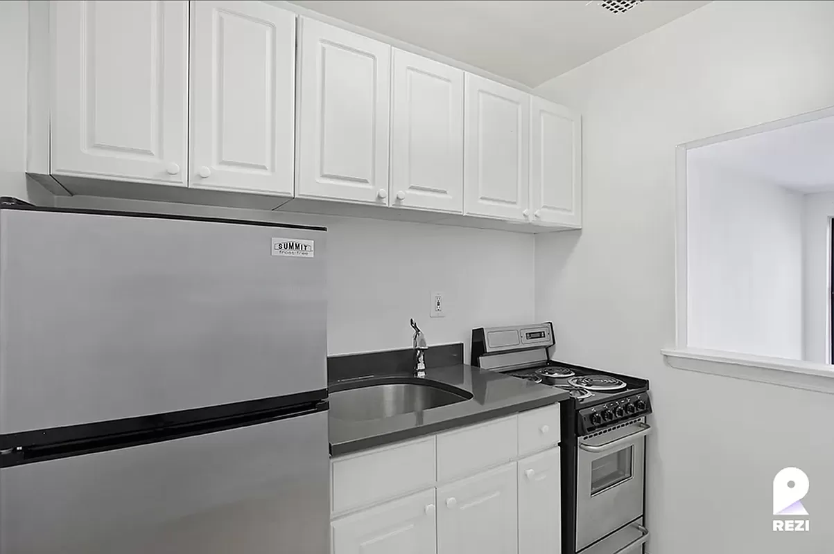 343 East 76th Street, Unit 4C Manhattan, NY 10021 - Photo 4 of 8 a kitchen with stainless steel appliances granite countertop white cabinets and a sink