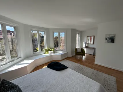 a large spacious bedroom with a large window and a wooden floor