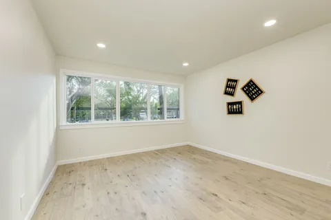 an empty room with wooden floor and windows