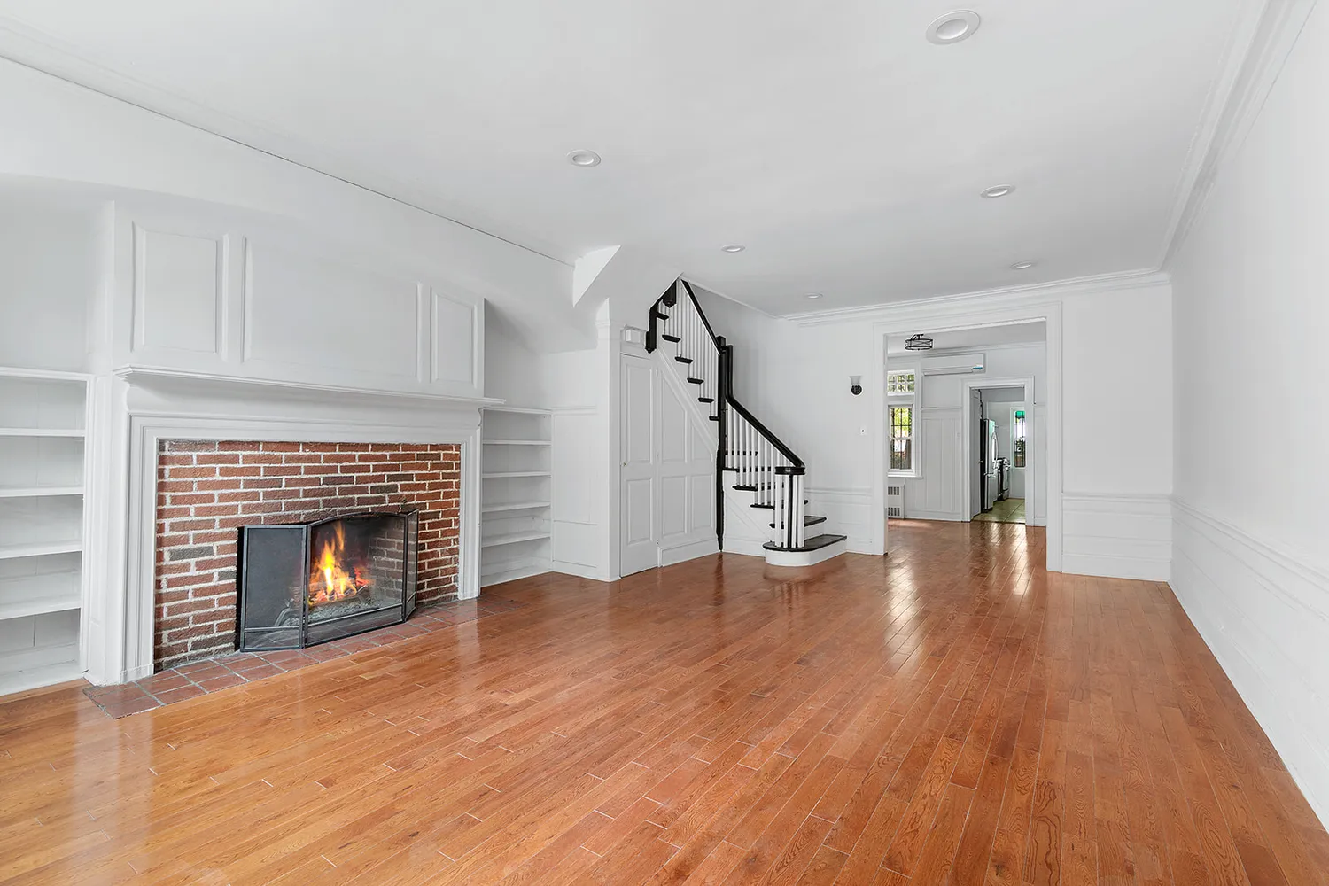 a view of an empty room with wooden floor fireplace and a window