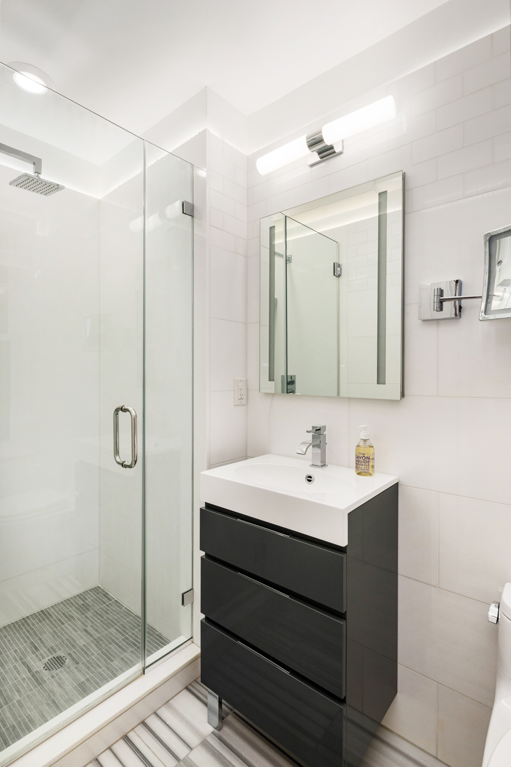 45 Christopher Street, Unit 2E Manhattan, NY 10014 - Photo 9 of 15 a bathroom with a sink a mirror a glass door a shower and a mirror