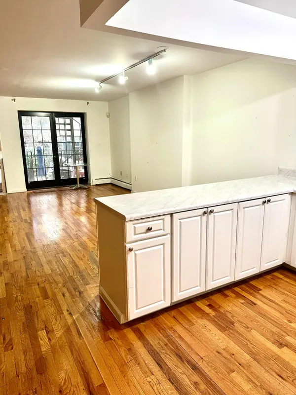 a view of an empty room with window and wooden floor
