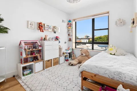 a bedroom with a bed a large window and book shelf