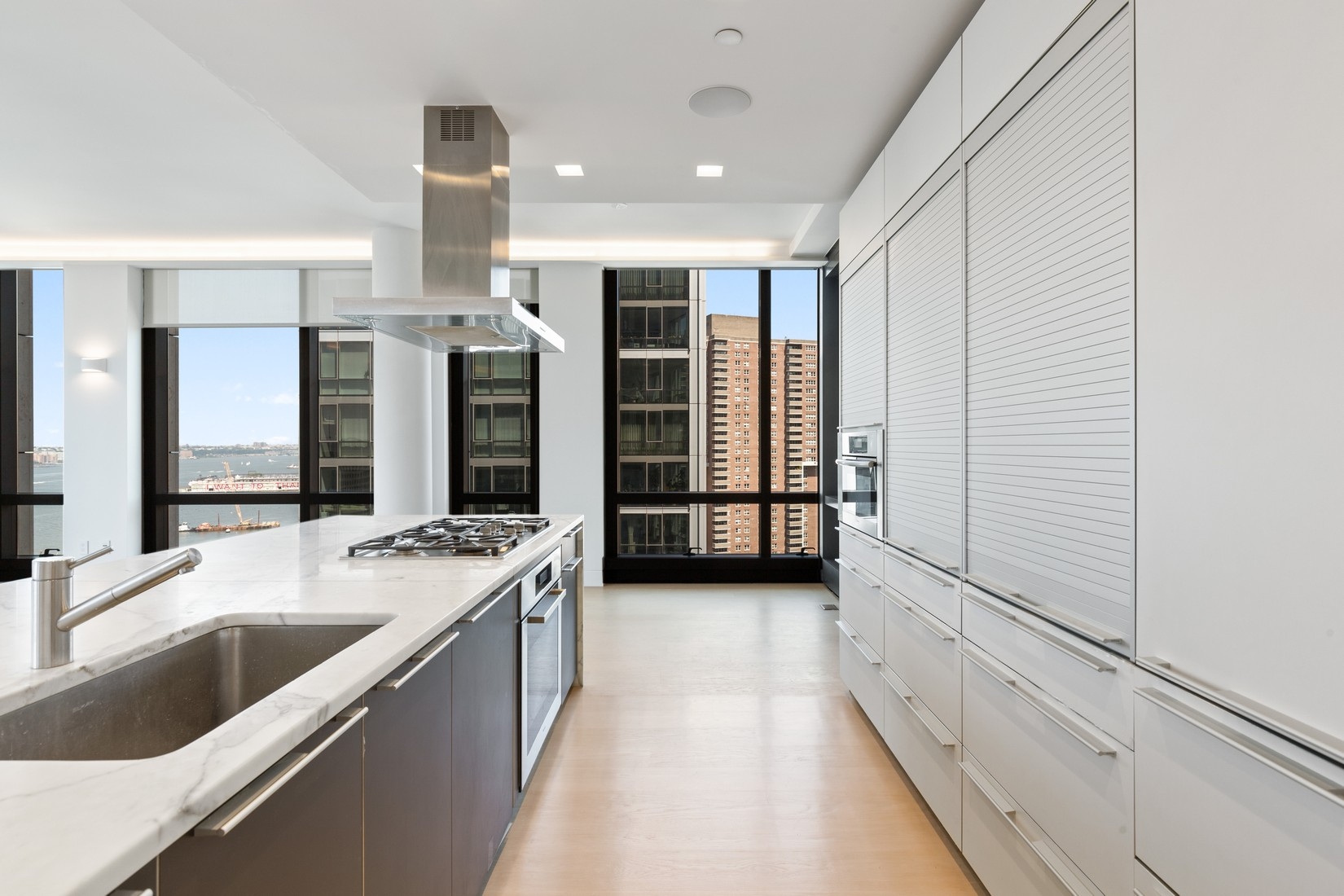 101 Warren Street, Unit 2420 Manhattan, NY 10007 - Photo 4 of 23 a large white kitchen with a large window and stainless steel appliances