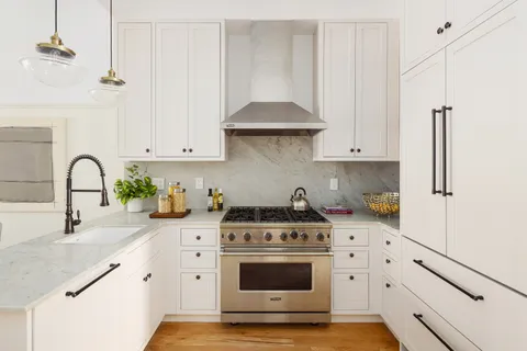 a kitchen with granite countertop white cabinets and white appliances