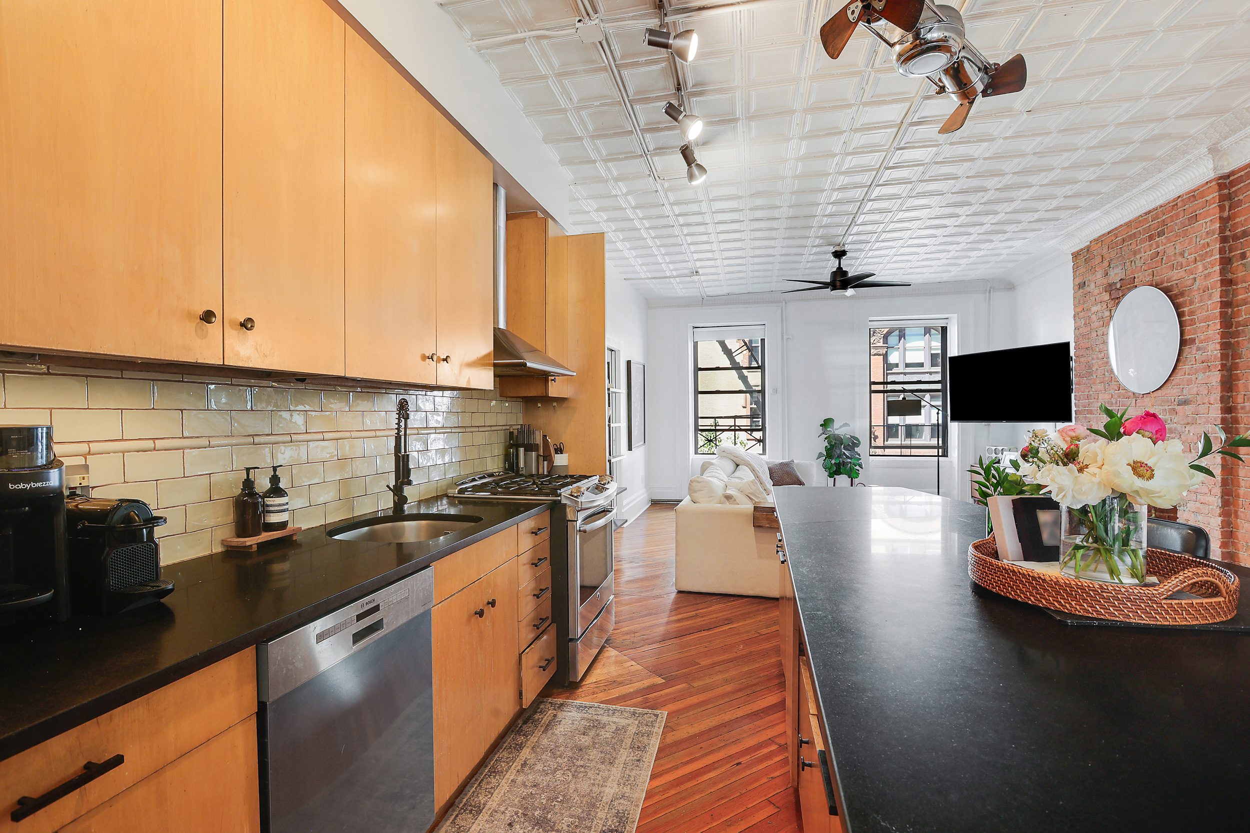 5 Great Jones Street Manhattan, NY 10012 - Photo 4 of 11 a kitchen with stainless steel appliances granite countertop a sink dishwasher stove refrigerator and microwave with wooden floor