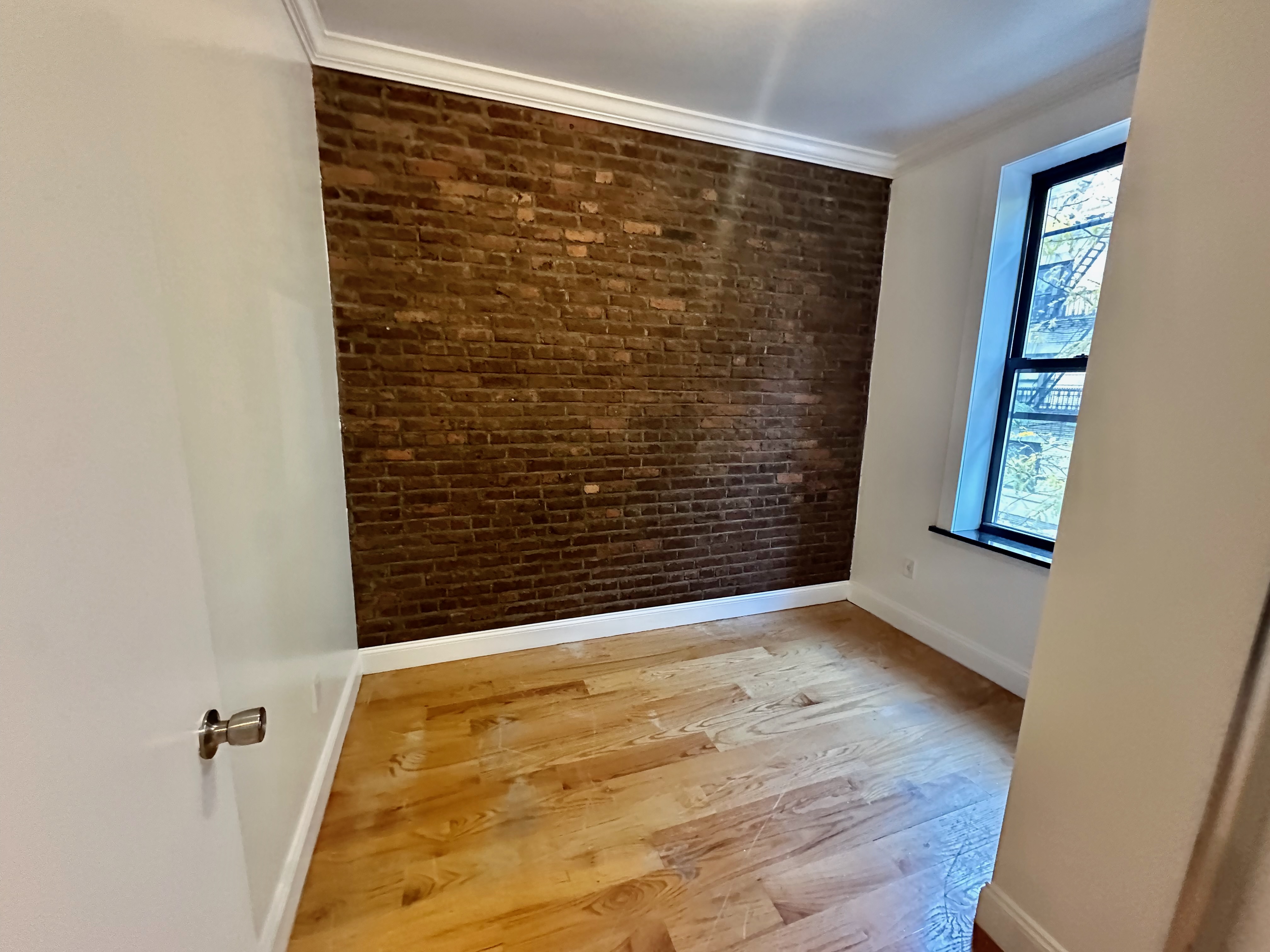 541 West 144th Street, Unit 4 Manhattan, NY 10031 - Photo 9 of 9 a view of an empty room with wooden floor and a window