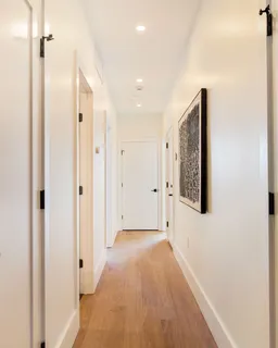 a view of a hallway with wooden floor and a bathroom
