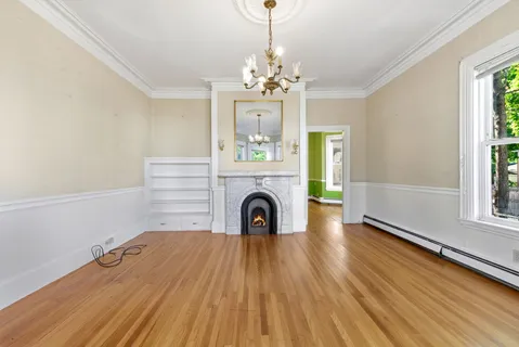 a view of an empty room with a window and wooden floor