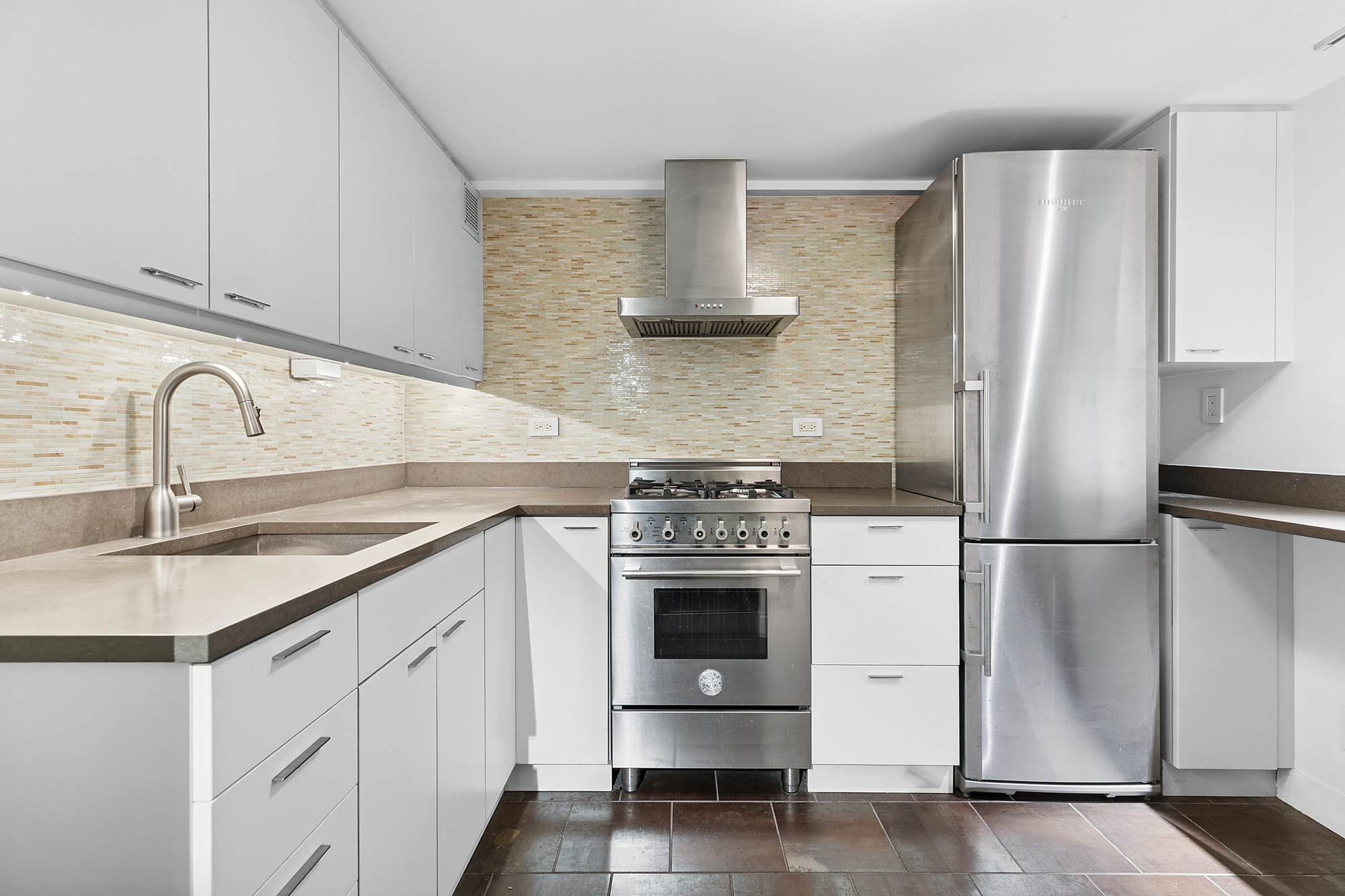 133 East 15th Street, Unit 1B Manhattan, NY 10003 - Photo 5 of 12 a kitchen with stainless steel appliances a refrigerator sink and cabinets