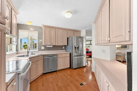 a kitchen with stainless steel appliances a stove a sink and a refrigerator with wooden floor
