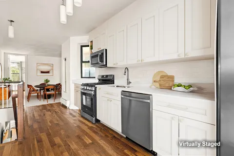 a kitchen with stainless steel appliances granite countertop a refrigerator a stove top oven a dining table and chairs with wooden floor