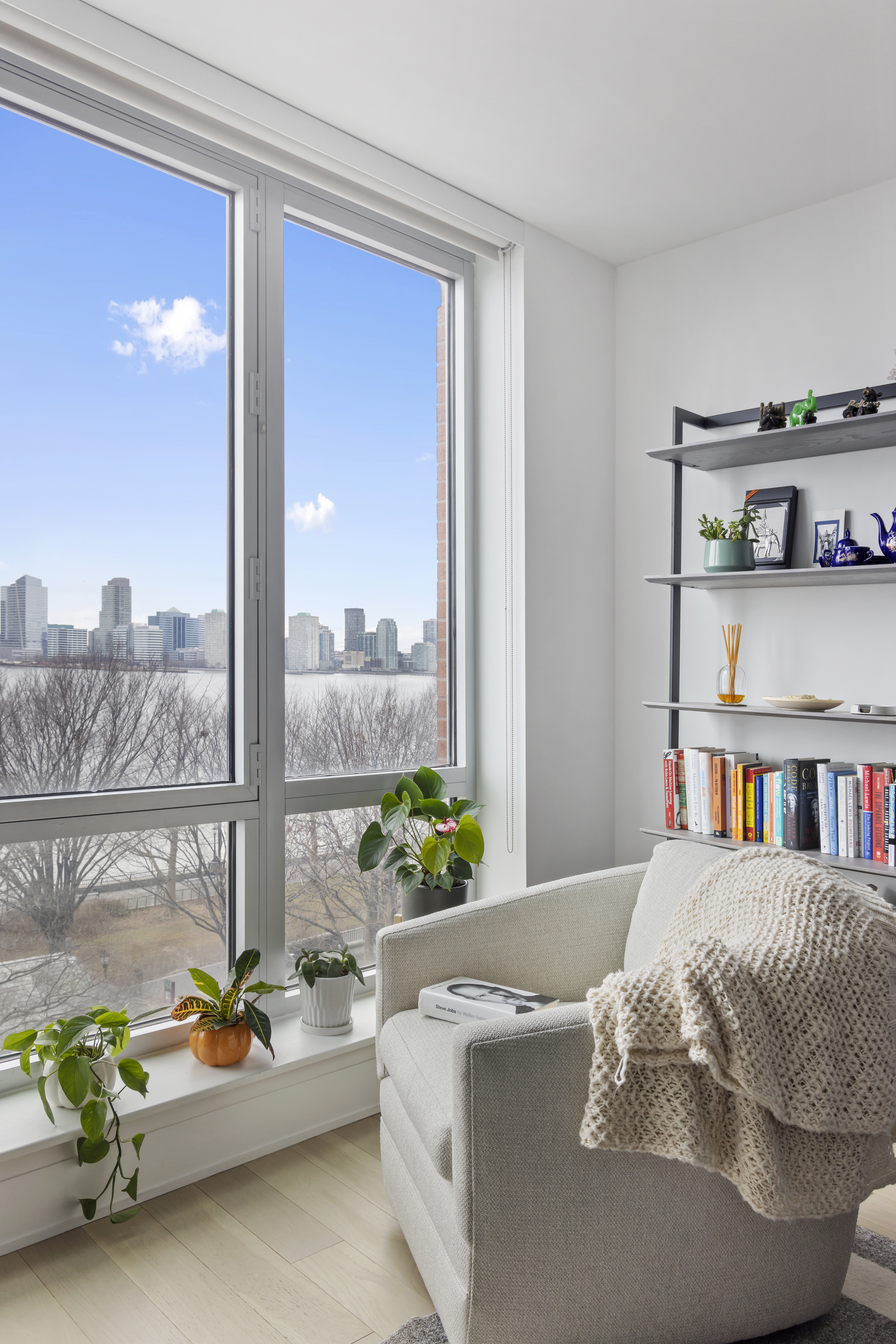 20 River Terrace, Unit 7K Manhattan, NY 10282 - Photo 3 of 9 a living room with furniture and a book shelf