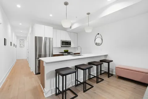 a kitchen with stainless steel appliances a table chairs in it and wooden floors