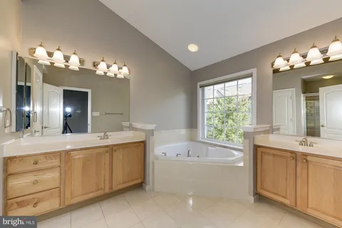 a bathroom with a tub double sink and a mirror