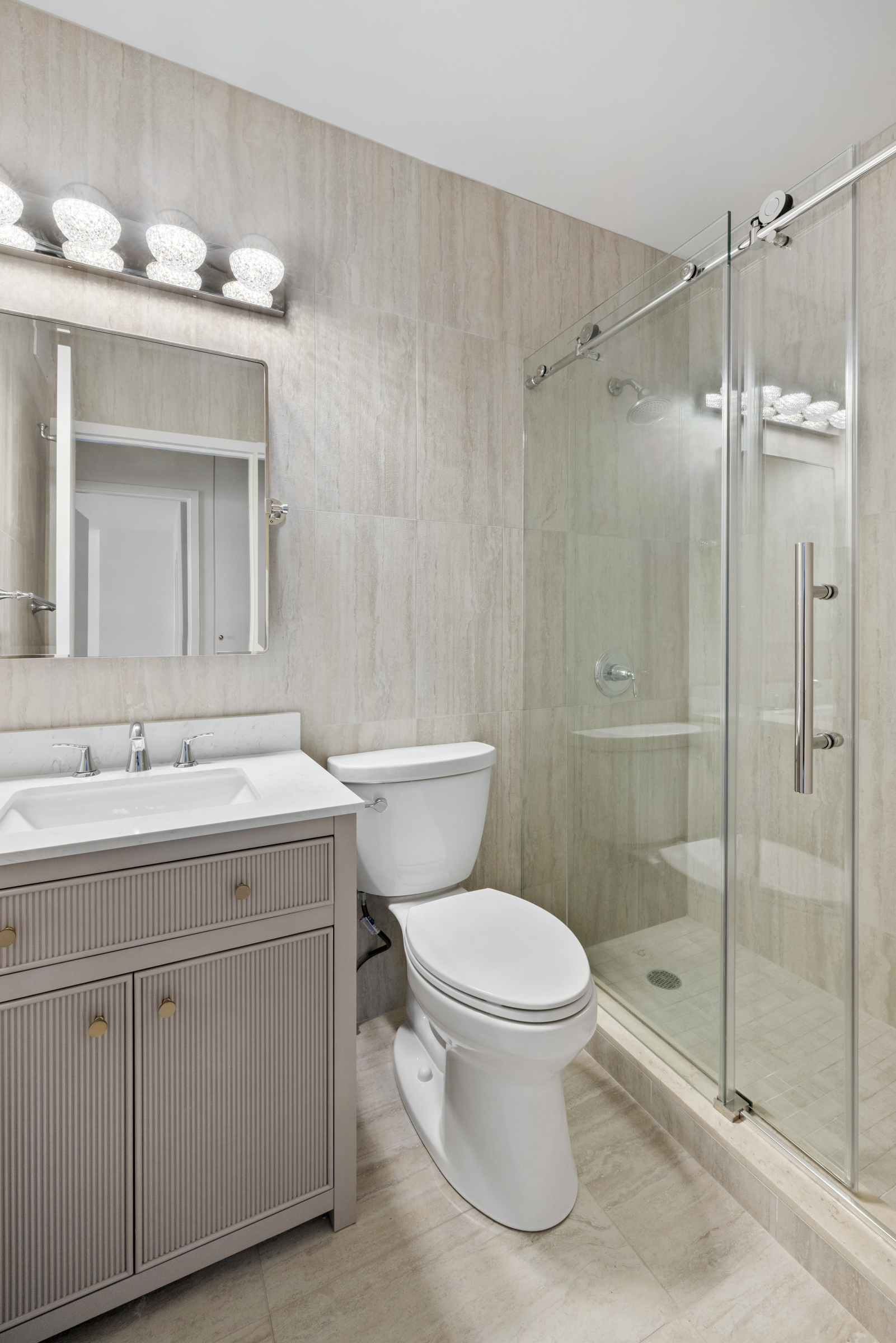 240 East 47th Street, Unit 27C Manhattan, NY 10017 - Photo 7 of 11 a bathroom with a shower sink vanity mirror and toilet