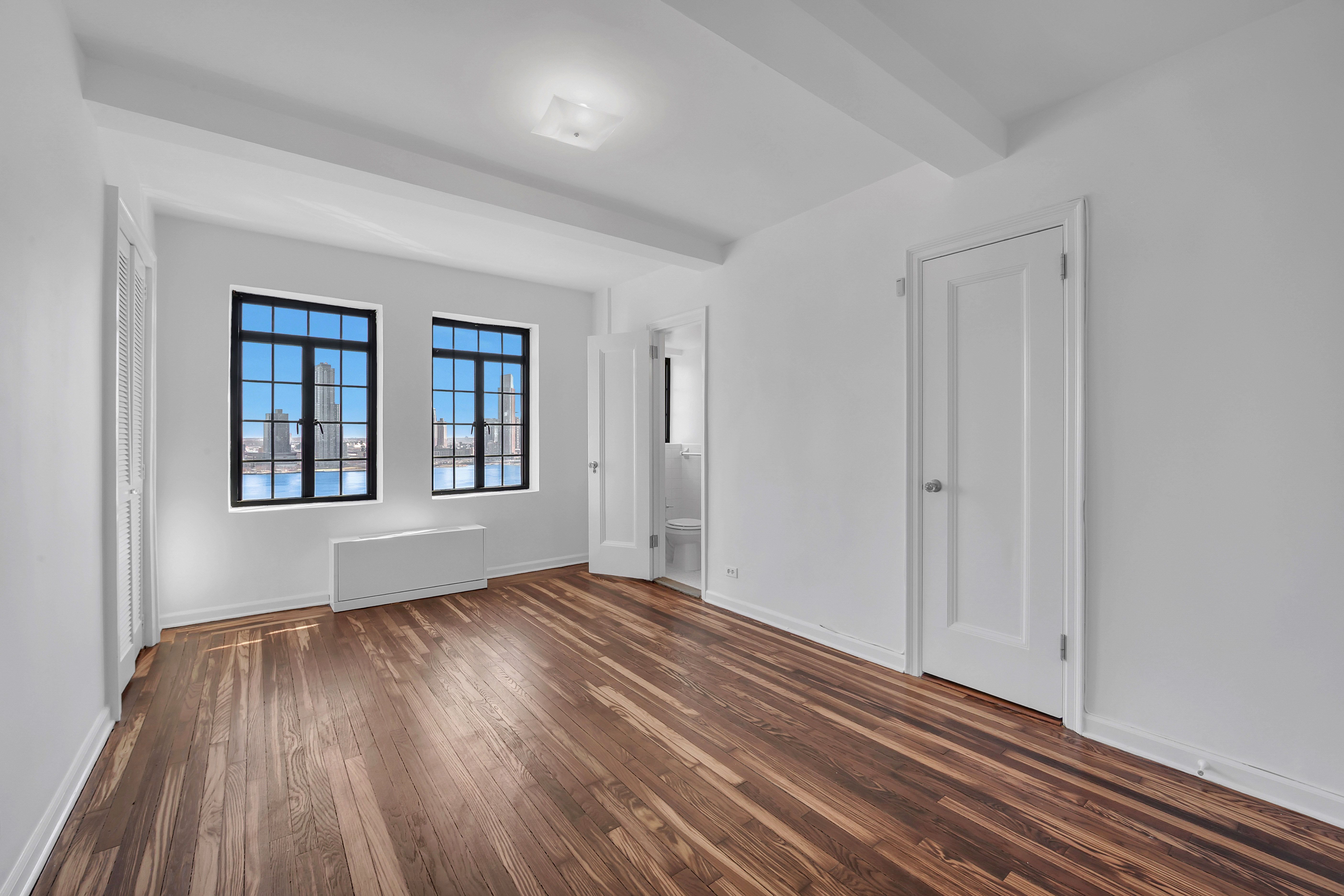 5 Tudor City Place, Unit 1126 Manhattan, NY 10017 - Photo 3 of 20 a view of an empty room with wooden floor and a window