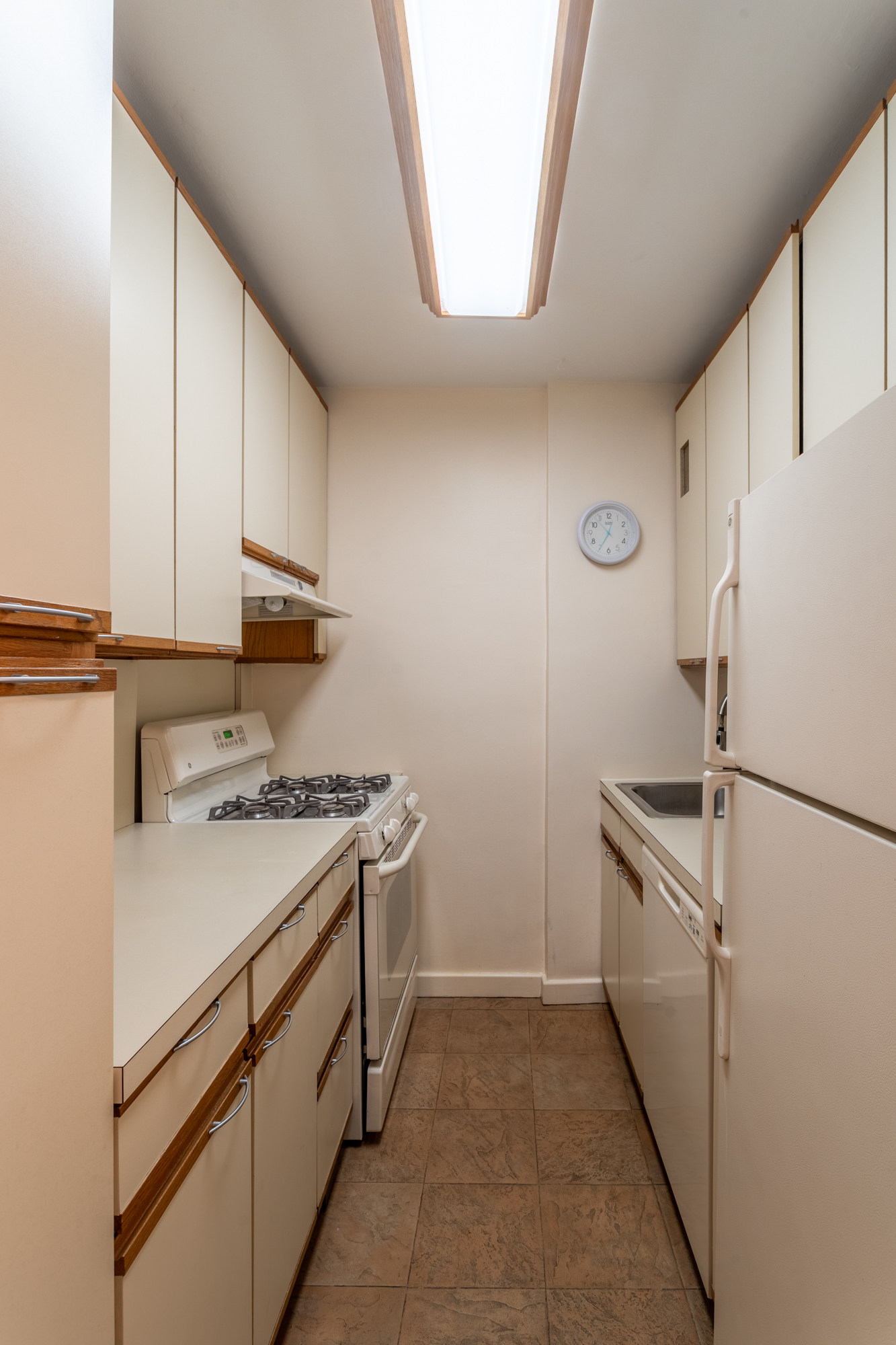315 East 65th Street, Unit 8F Manhattan, NY 10065 - Photo 7 of 11 a kitchen with white cabinets and white appliances