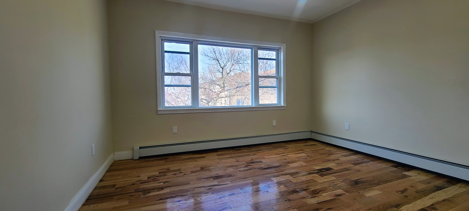 97-08 Plattwood Avenue, Unit 2 Queens, NY 11417 - Photo 6 of 10 an empty room with wooden floor and windows