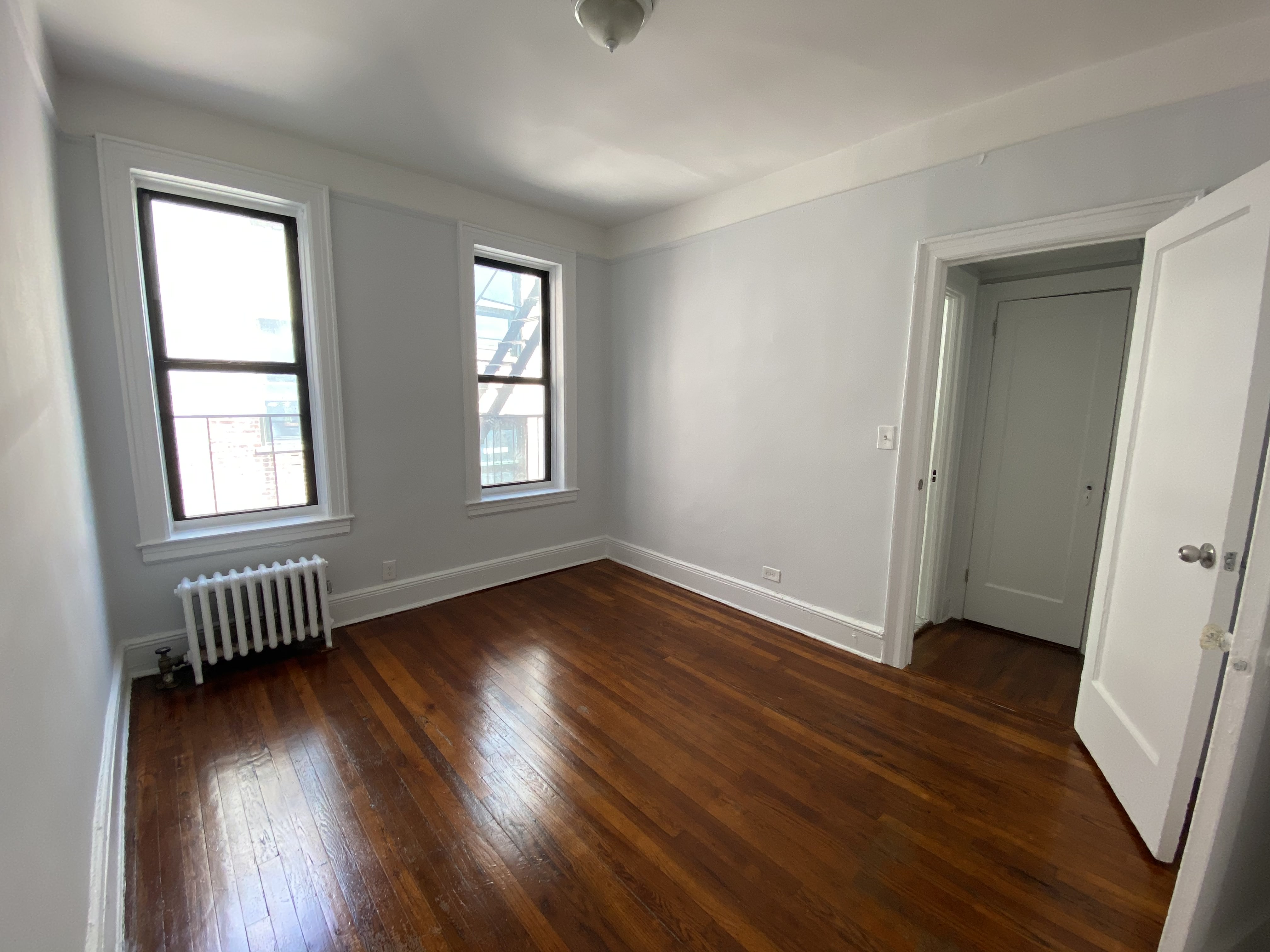 28-23 42nd Street, Unit C3 Queens, NY 11103 - Photo 5 of 6 an empty room with wooden floor and windows