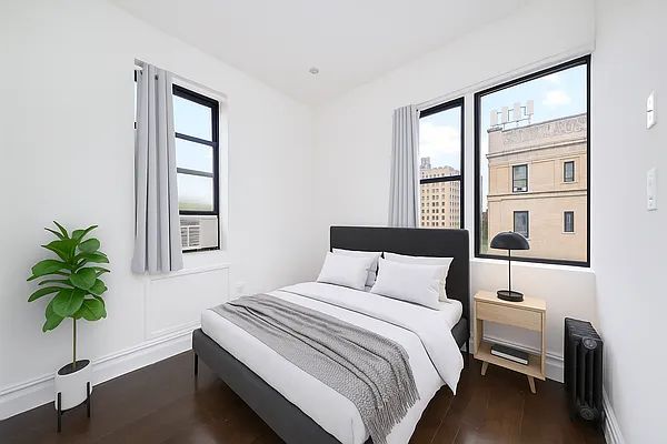 a bedroom with a bed and a potted plant next to a window